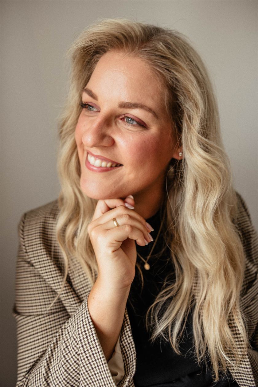 Lara Holzhofer im karierten Blazer, den Blick zur Seite gerichtet